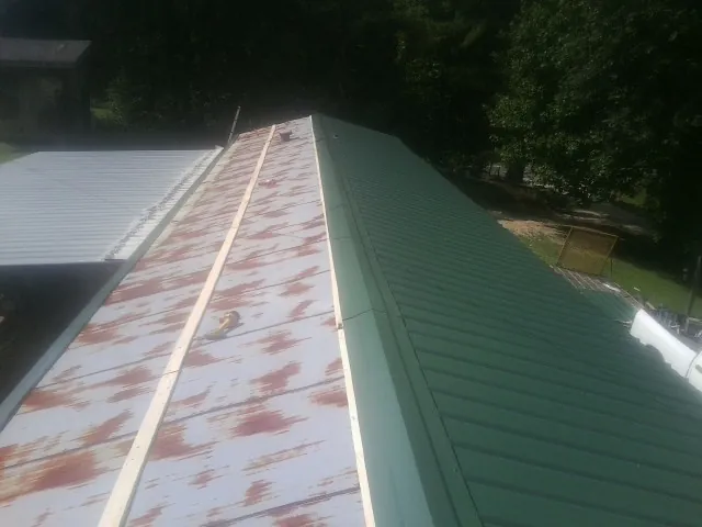 Old rusted panels beside newly installed green metal roofing — Wind Damage Roof Repair by Roofing Brothers in Glenbrook