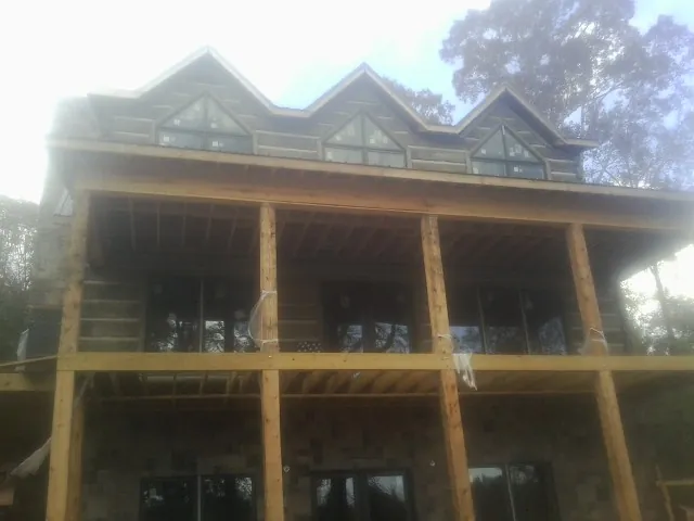 Dormers and porch framing on a large log home under construction — Roof Coating work by our crew in Glenbrook