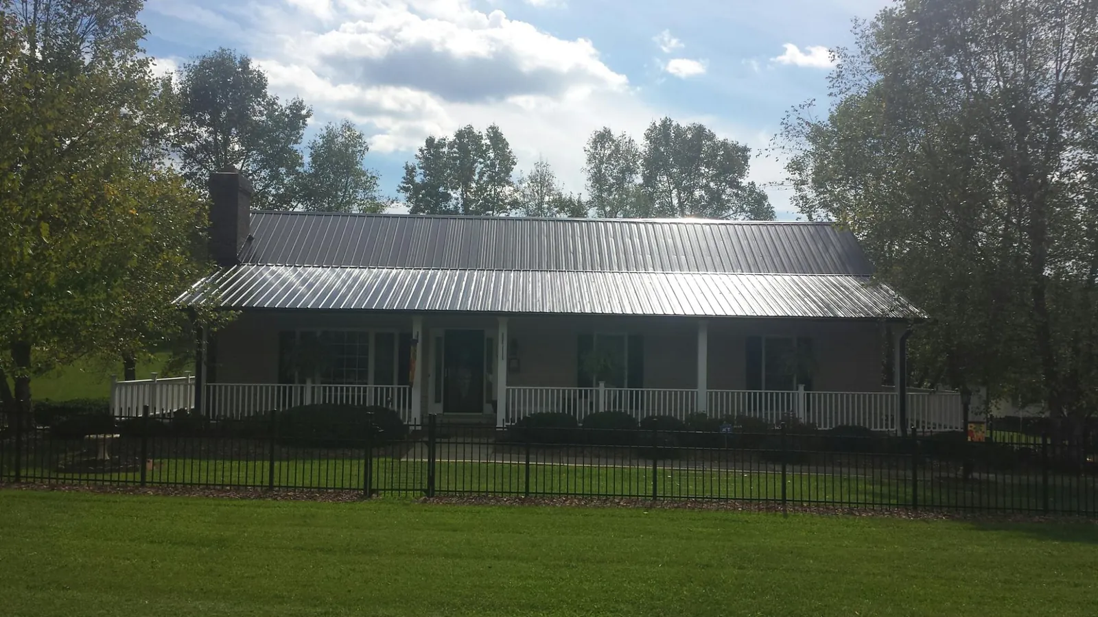 Gray metal roof on a brick ranch with a full width front porch — Gutter Guard Installation work by our crew in Glenbrook