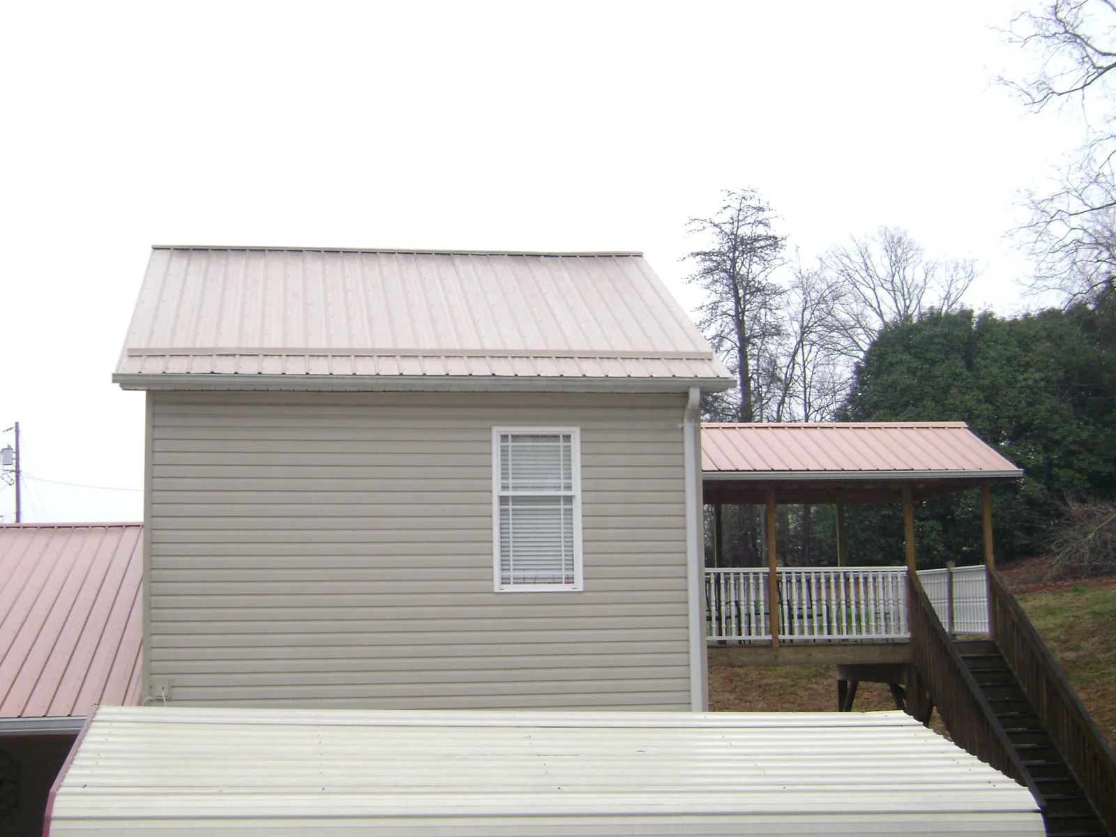 Tan metal roofs on a two story addition and attached porch, from a Roof Replacement job in Glenbrook