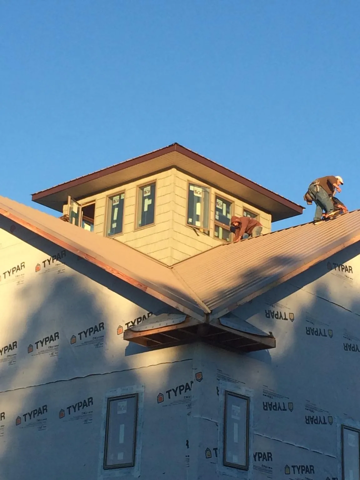 Roofers working around a rooftop cupola on a new metal roof at sunset — Roof Waterproofing in Glenbrook by Roofing Brothers